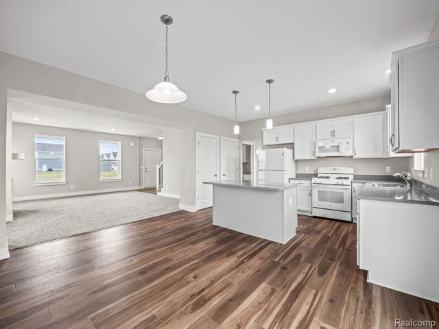 kitchen with white appliances, a kitchen island, white cabinetry, hanging light fixtures, and dark hardwood / wood-style floors