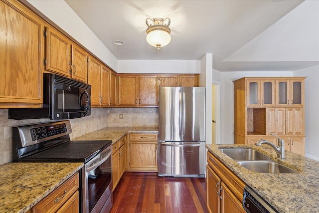 kitchen with black appliances, light stone counters, tasteful backsplash, and sink