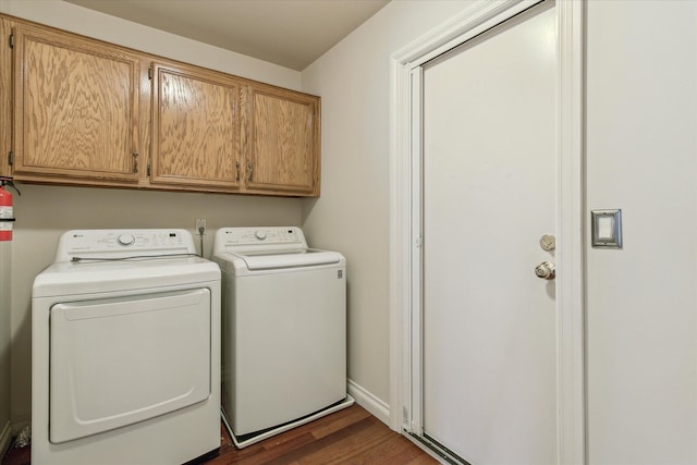 laundry area featuring washing machine and clothes dryer, dark wood-type flooring, and cabinets