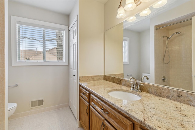 bathroom with vanity, toilet, a tile shower, and tile patterned flooring