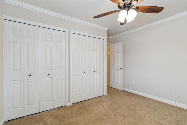 unfurnished bedroom with ceiling fan, light colored carpet, ornamental molding, and two closets