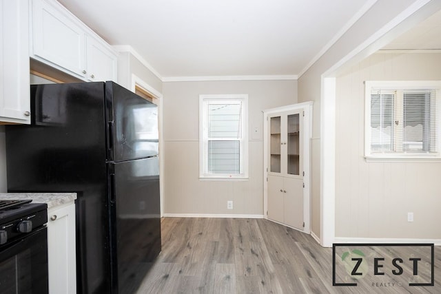 kitchen featuring ornamental molding, stove, white cabinets, and light hardwood / wood-style flooring