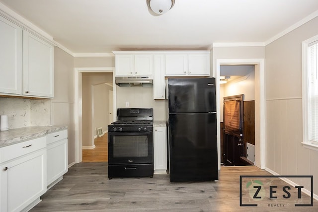 kitchen featuring white cabinetry, black appliances, light wood-type flooring, ornamental molding, and backsplash