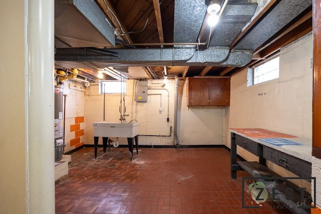 basement with gas water heater, sink, and electric panel