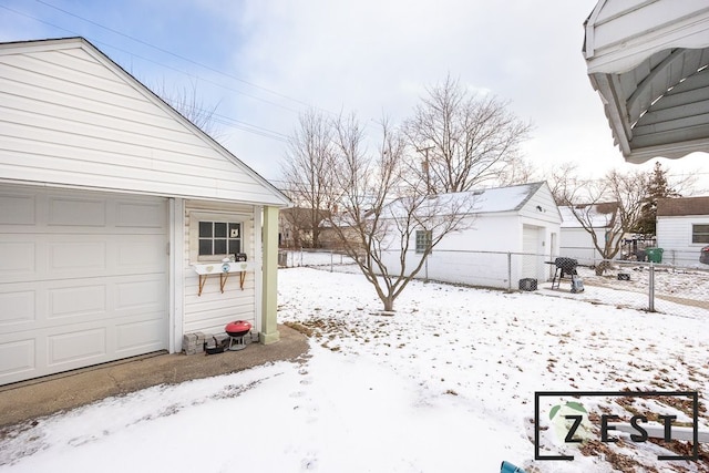 yard layered in snow featuring a garage and an outdoor structure