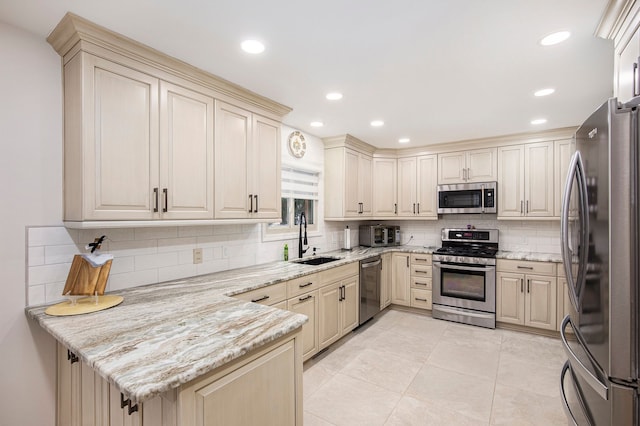 kitchen featuring light stone counters, sink, decorative backsplash, and appliances with stainless steel finishes