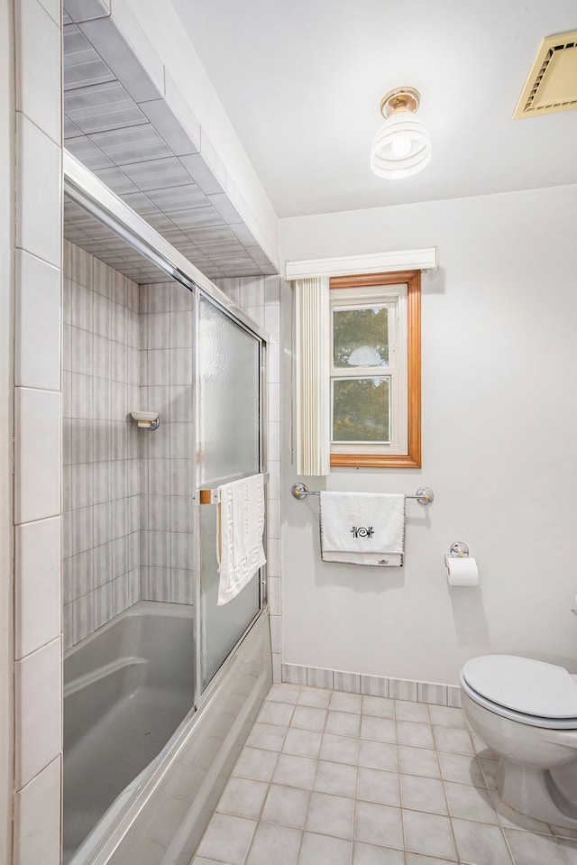 bathroom with enclosed tub / shower combo, toilet, and tile patterned flooring