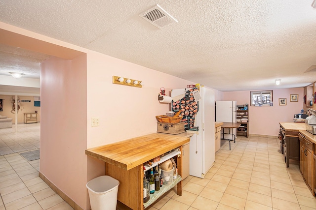 kitchen with a textured ceiling and light tile patterned flooring