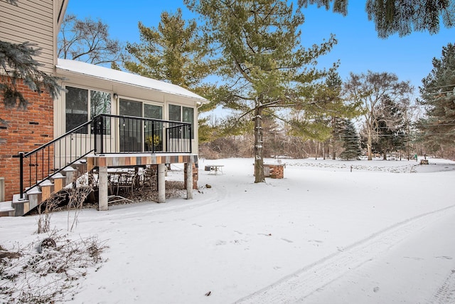 snowy yard featuring a sunroom