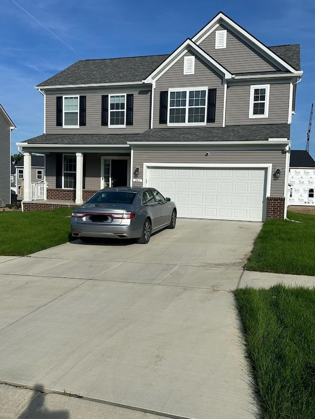 view of front property featuring covered porch, a garage, and a front lawn