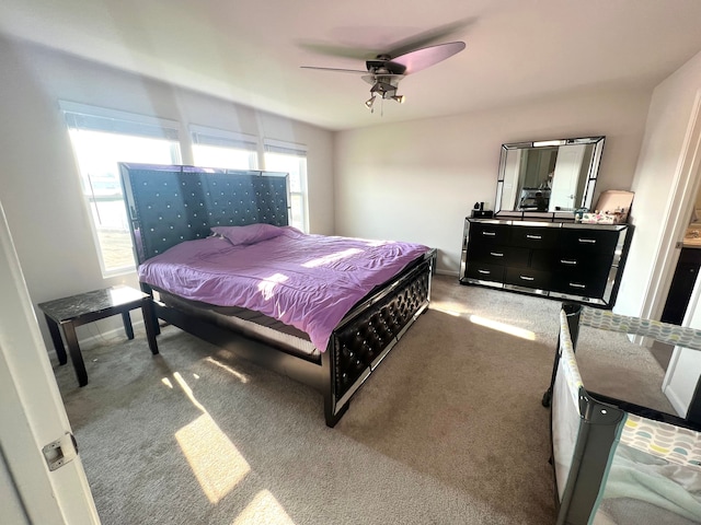 bedroom featuring ceiling fan, dark carpet, and multiple windows