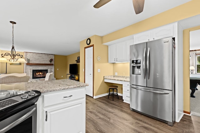 kitchen with light stone counters, hanging light fixtures, white cabinets, and appliances with stainless steel finishes