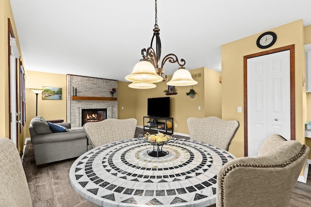 dining room with a brick fireplace and dark wood-type flooring