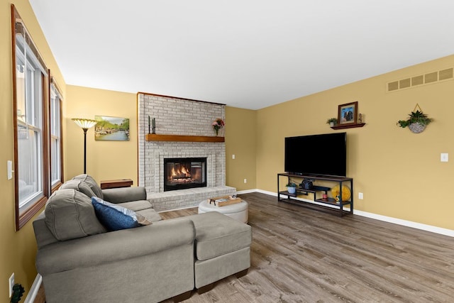 living room with wood-type flooring and a brick fireplace