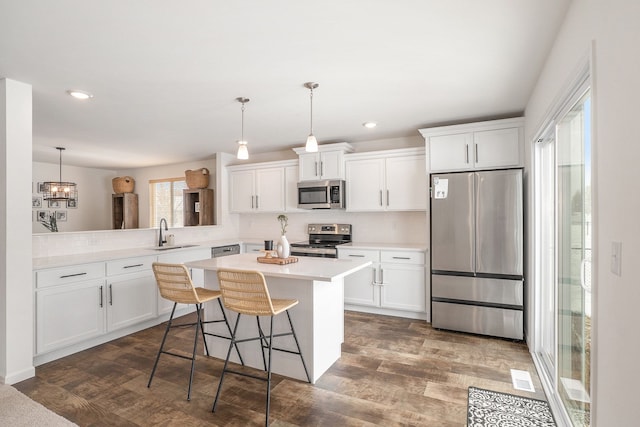 kitchen featuring white cabinets, sink, appliances with stainless steel finishes, and a kitchen breakfast bar