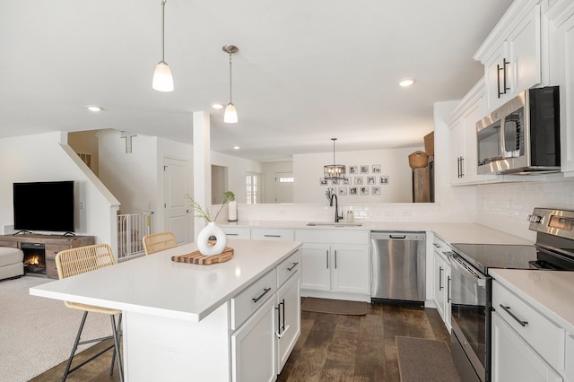 kitchen with a center island, stainless steel appliances, sink, hanging light fixtures, and a breakfast bar