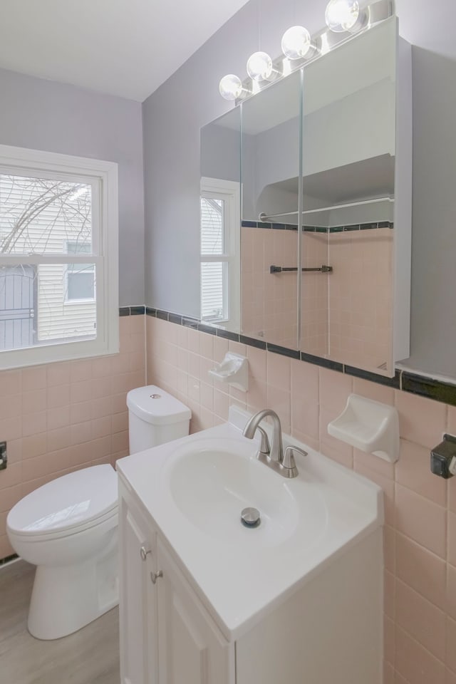 bathroom with vanity, toilet, walk in shower, and tile walls