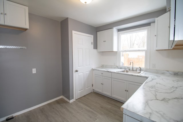 kitchen with sink, light wood-type flooring, and white cabinetry