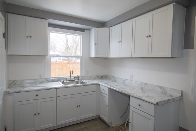 kitchen with light stone countertops, sink, white cabinets, and dark hardwood / wood-style floors