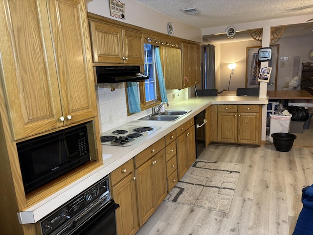 kitchen with sink, tasteful backsplash, light hardwood / wood-style floors, a textured ceiling, and black appliances