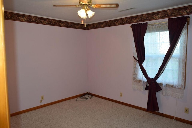 carpeted empty room featuring ornamental molding, visible vents, baseboards, and a ceiling fan