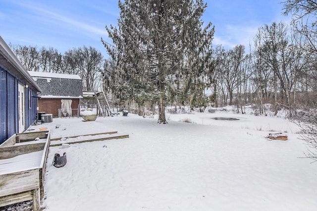 snowy yard with central AC and a fire pit