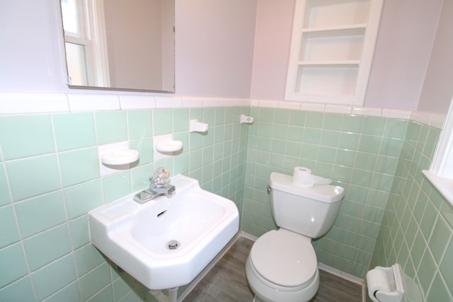 bathroom featuring tile walls, sink, hardwood / wood-style flooring, built in shelves, and toilet