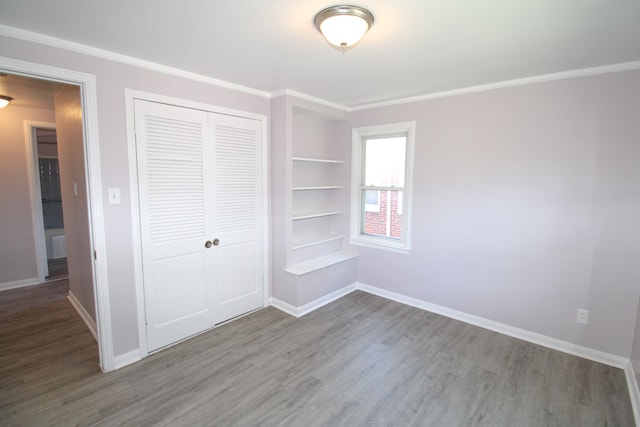 unfurnished bedroom featuring wood-type flooring, a closet, and ornamental molding