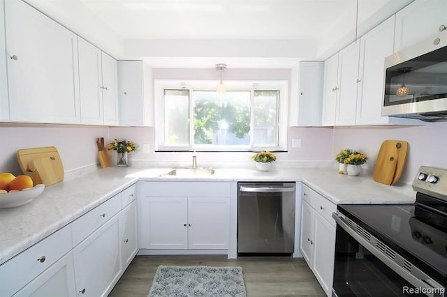 kitchen featuring white cabinets, stainless steel appliances, sink, and decorative light fixtures