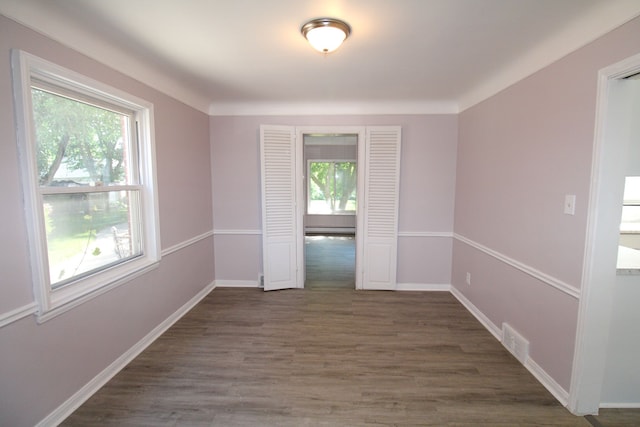 unfurnished room featuring a wealth of natural light and dark hardwood / wood-style floors