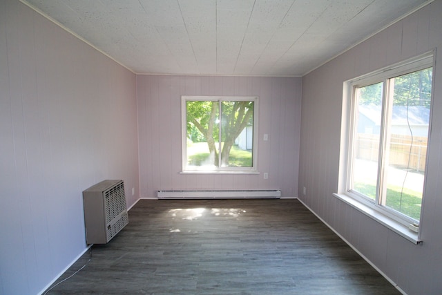 spare room with dark hardwood / wood-style flooring, baseboard heating, and plenty of natural light