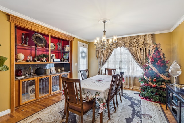 dining room with crown molding, hardwood / wood-style flooring, and a notable chandelier