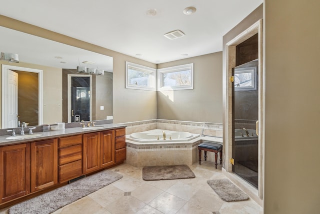 bathroom with tiled tub, vanity, and tile patterned flooring