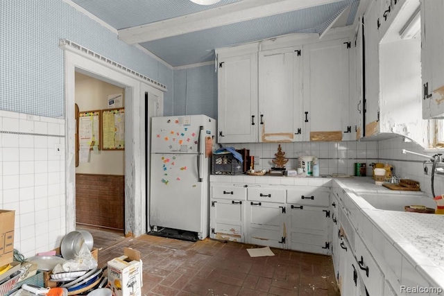 kitchen with crown molding, sink, backsplash, white cabinetry, and white fridge