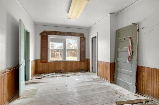 miscellaneous room with light wood-type flooring and wooden walls