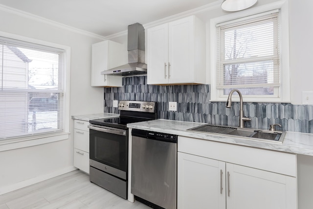 kitchen with wall chimney exhaust hood, sink, white cabinets, tasteful backsplash, and stainless steel appliances