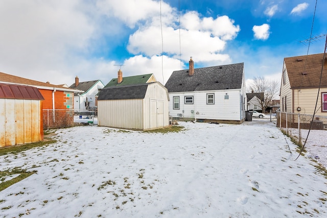 snow covered house featuring a storage shed