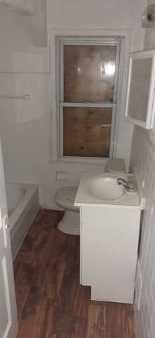 bathroom with a tub, hardwood / wood-style flooring, toilet, and vanity