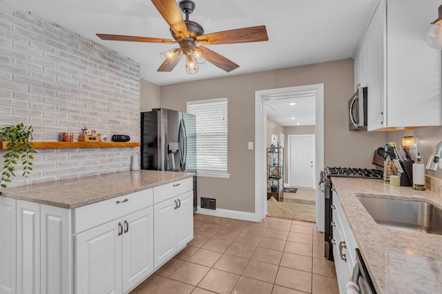 kitchen featuring light tile patterned floors, white cabinets, sink, stainless steel appliances, and light stone counters