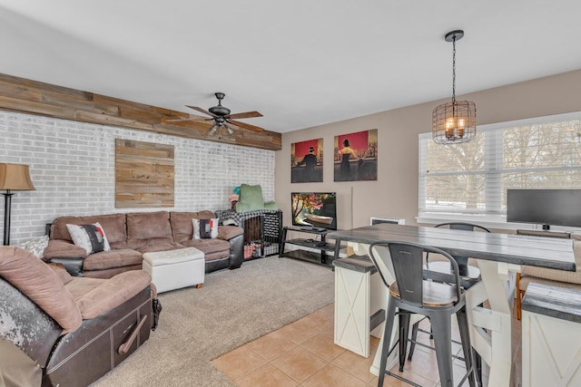 living room featuring ceiling fan with notable chandelier, brick wall, and light carpet