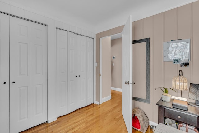 bedroom with light hardwood / wood-style flooring and two closets