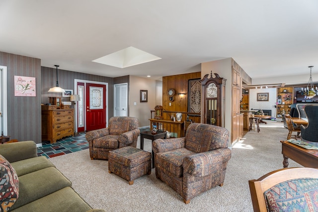 carpeted living room with wooden walls and a brick fireplace