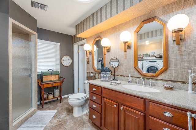 bathroom with tile patterned floors, toilet, a shower with shower door, washer / dryer, and vanity