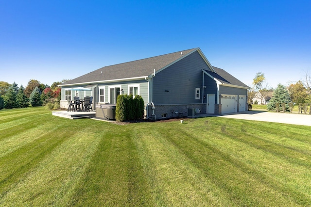 back of house featuring central air condition unit, driveway, an attached garage, and a lawn