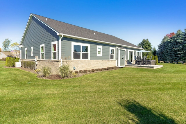 back of house featuring a patio area, brick siding, and a lawn