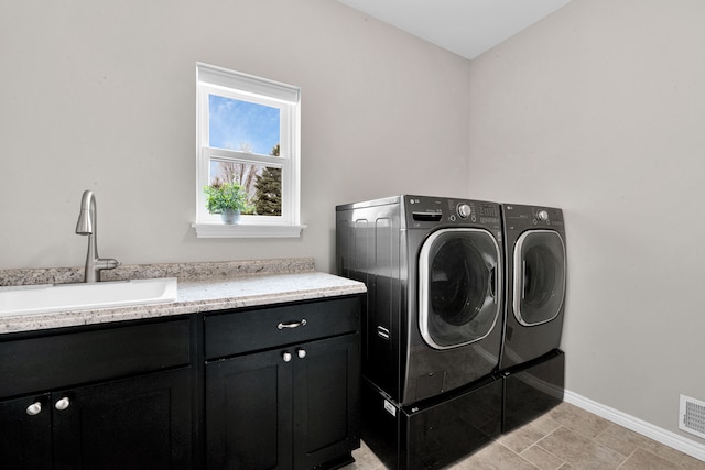 washroom featuring cabinet space, baseboards, washer and clothes dryer, and a sink