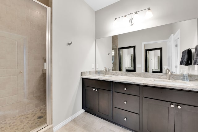 bathroom with double vanity, a sink, a shower stall, baseboards, and tile patterned floors