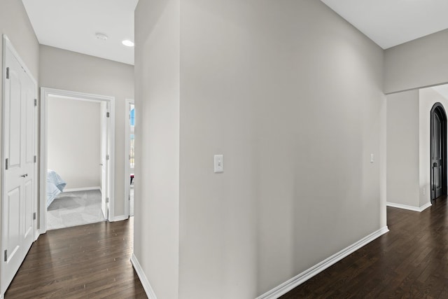 hall featuring dark wood-type flooring and baseboards