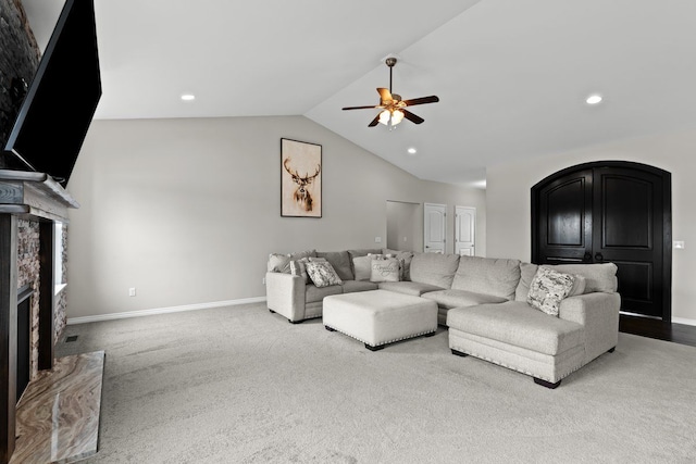 living area featuring lofted ceiling, recessed lighting, ceiling fan, a stone fireplace, and baseboards