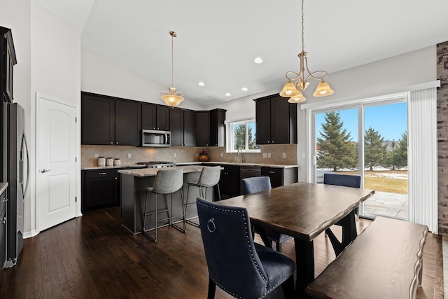 dining room with an inviting chandelier, high vaulted ceiling, dark wood-type flooring, and recessed lighting